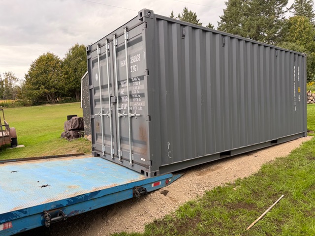 Shipping container sliding off a tilt-bed trailer
